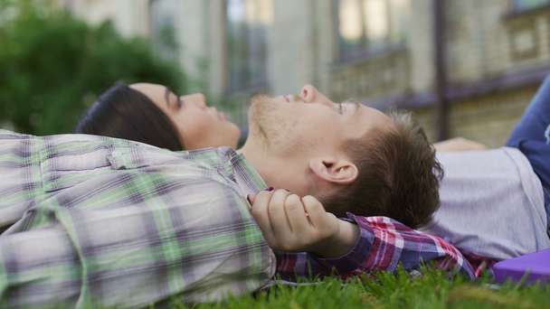 Loving couple of mixed-race teens lying on lawn, enjoying date. First love - Felvétel, videó