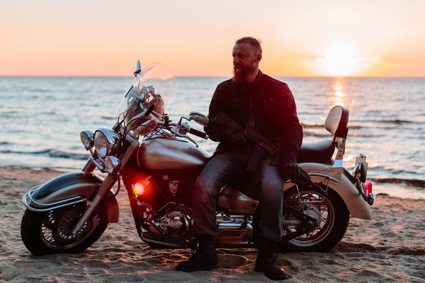 man on a motorcycle chopper on the beach at sunset - Фото, зображення