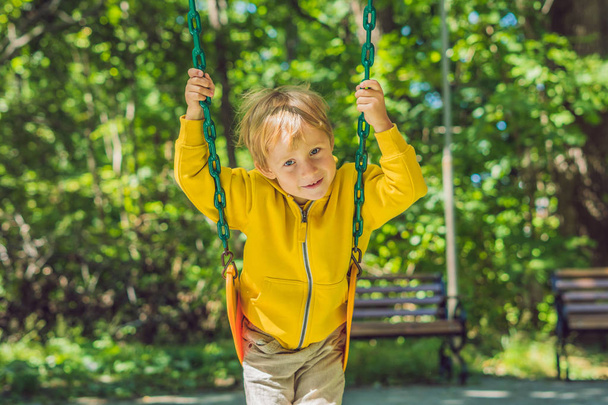A boy on a swing on a playground - Fotoğraf, Görsel