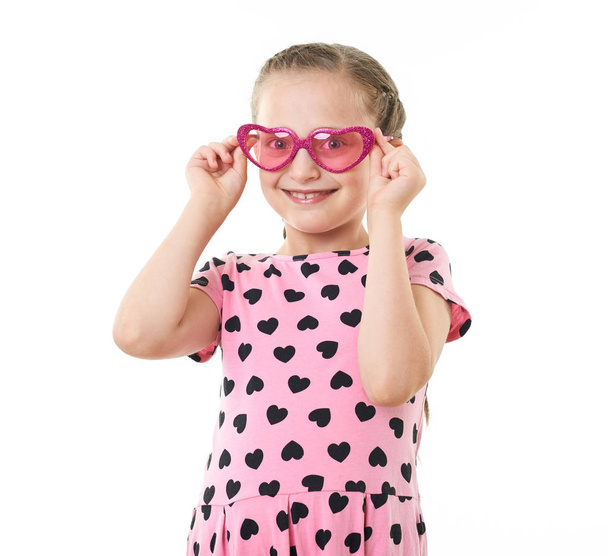 hübsche kleine Mädchen Studioporträt, in rosa mit Herzformen gekleidet, weißer Hintergrund - Foto, Bild