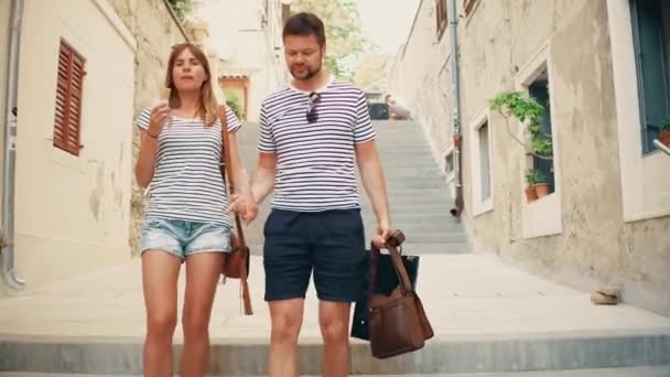 Young couple walking down pedestrian Mediterranean town street on vacation - Materiał filmowy, wideo