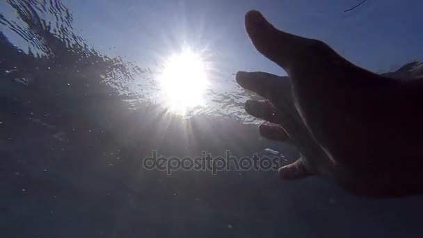 Point of view of man drowning in the sea or ocean. Arm asking for help and trying to reach to the sun. Male hand stretches from under the water to sunrays. Slow motion POV - Footage, Video