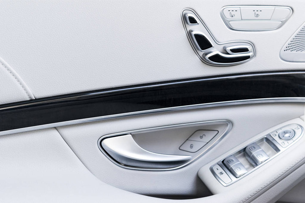 高級乗用車の電源席コントロール ボタンを使ってドアのハンドル。高級モダンな車のホワイト レザー インテリア。現代の車のインテリアの詳細 - 写真・画像