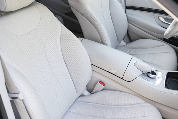 White leather interior of the luxury modern car. Leather comfortable white seats and multimedia. Steering wheel and dashboard. automatic gear stick. Car interior details - 写真・画像