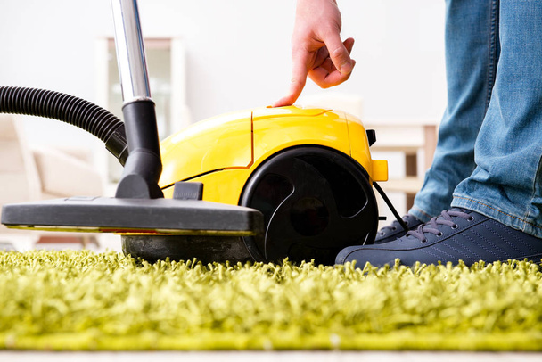 Man cleaning the floor carpet with a vacuum cleaner close up - Photo, image