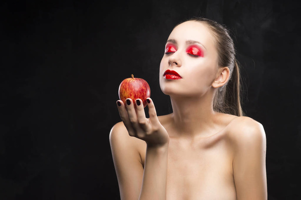 girl holds apple with the red eyeshadow covered with gloss - Zdjęcie, obraz