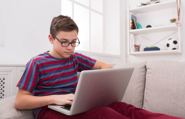 Teenage boy using laptop on couch at home - Photo, Image
