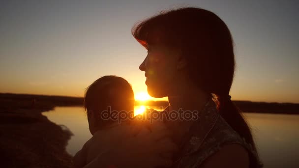 Mom holds child in arms of sun at sunset. Slow motion. - Footage, Video