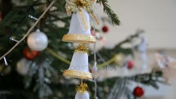 goldene Spielzeugglocken hängen am Weihnachtsbaum inmitten blinkender farbiger Girlanden, Nahaufnahme - Filmmaterial, Video