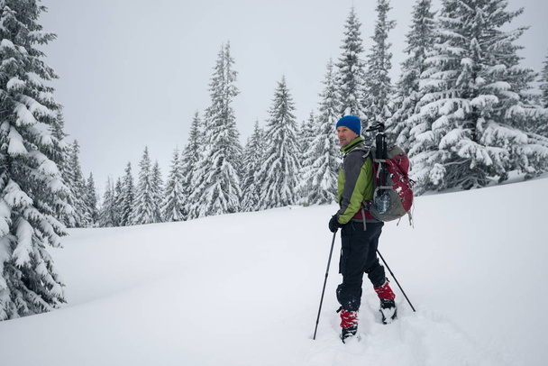 Smiling traveler is standing in a deep snow - Foto, afbeelding