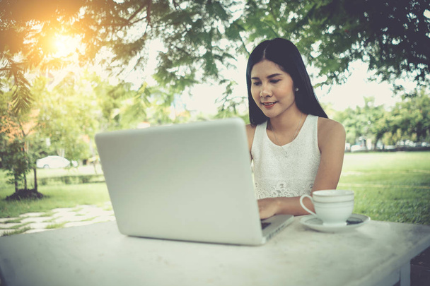 Muchacha joven atractiva con el ordenador portátil al aire libre. Hermosa mujer de trabajo
 - Foto, imagen