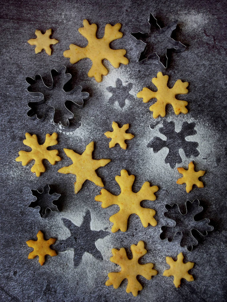 Galletas de bizcocho de Navidad en forma de copos de nieve rociando azúcar y cortadores de galletas. Concepto de tarjeta de Navidad
. - Foto, imagen