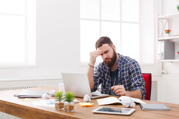 Müder gestresster männlicher Programmierer mit Laptop im modernen weißen Büro - Foto, Bild