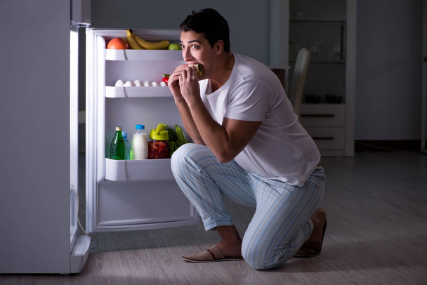 Man aan de koelkast 's nachts aan het eten - Foto, afbeelding