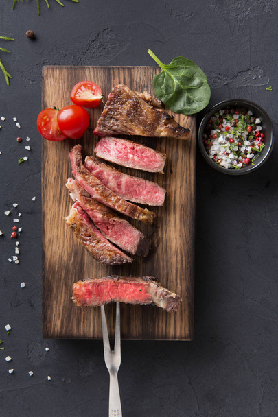 Rib eye steaks and spices on wood at black background - Photo, Image