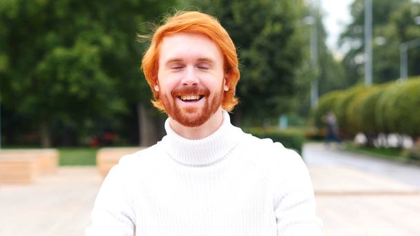 Lachende onschuldige jonge Man met rode haren, buiten - Foto, afbeelding