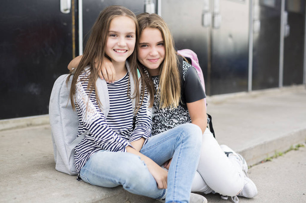 Portrait of two pre teenage girls studying outdoors in school yard - Foto, immagini