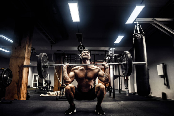 Muscular fitness man doing deadlift a barbell over his head in modern fitness center. Functional training. - Foto, immagini