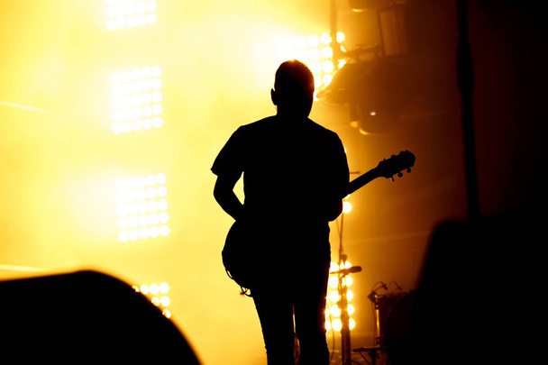 Силуэт-гитарист, гитарист выполняют на сцене концерт. - Фото, изображение