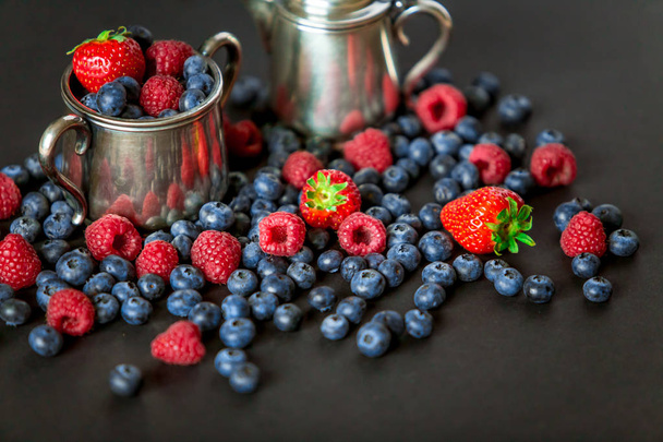 Contexte de framboises, fraises et bleuets. Berry sur fond noir avec espace de copie. Concept d'été et d'alimentation saine, vue de dessus ou plat
. - Photo, image