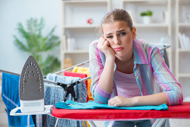 Mujer triste planchando ropa en casa - Foto, imagen