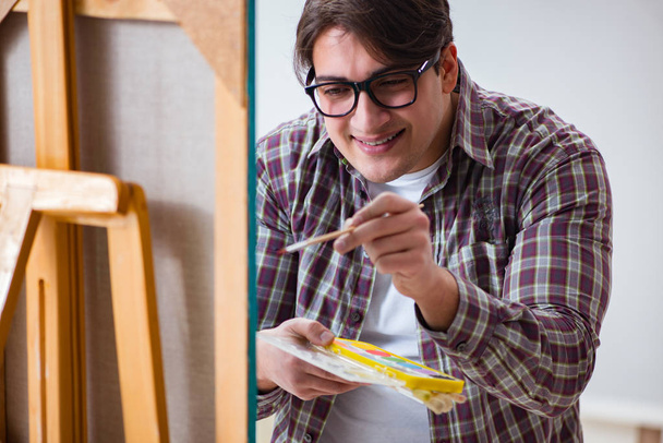 Молодий чоловік художник малює картини в яскравій студії
 - Фото, зображення