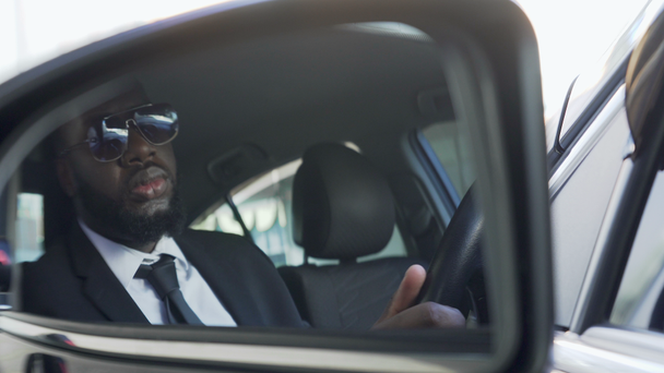 Afro-Amerikaanse in zonnebril rijden auto, kijken in zijaanzicht spiegel, bodyguard - Video