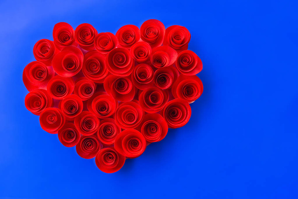 Червоні троянди з паперу у формі серця на синьому фоні
. - Фото, зображення