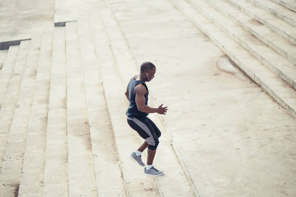 Jeune athlète africain accélère avec énergie dans les gradins
 - Photo, image