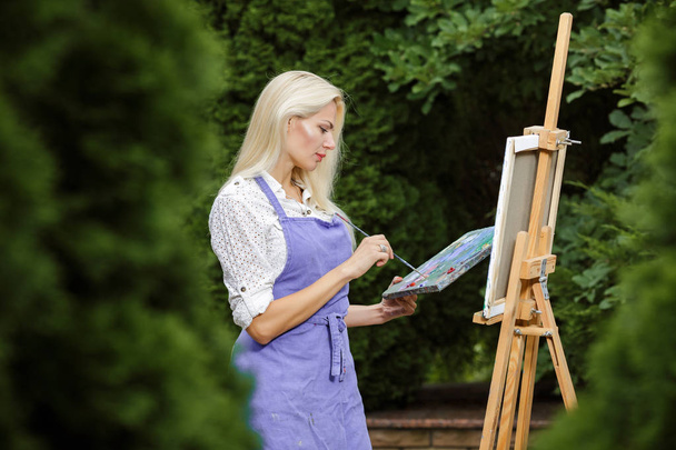 woman artist with a brush in her hand draws on canvas - Foto, Imagem