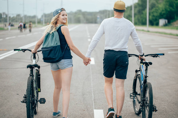 young couple walking bikes together on the road - Foto, immagini