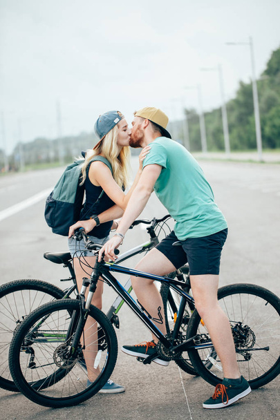Beautiful young couple in love walking with bicycles, kissing and hugging - Φωτογραφία, εικόνα