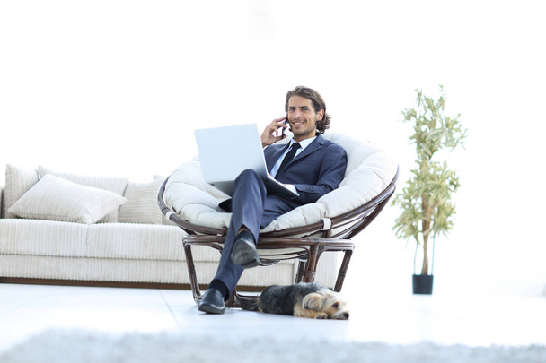 business man talking on a smartphone sitting in the living room - Fotó, kép