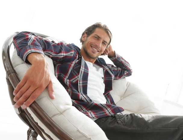 serious guy rests sitting in a large comfortable chair. side view. - Foto, imagen