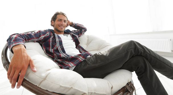 serious guy rests sitting in a large comfortable chair. side view. - Fotoğraf, Görsel