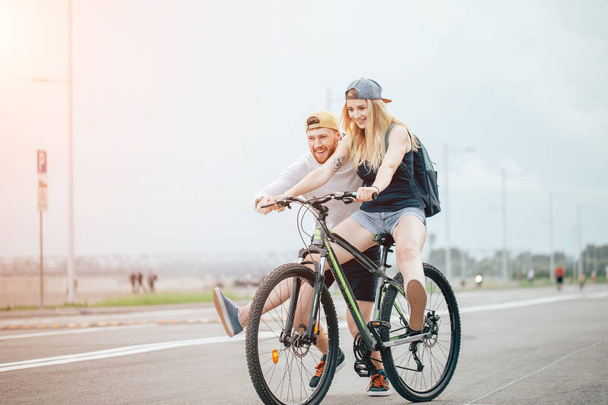 girl on bike, guy runs. boy teaches girl to ride a bike. Morning Meadow. - Φωτογραφία, εικόνα