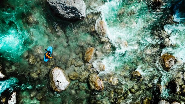 An extreme whitewater Kayaker padding on the Emerald waters of Soca river, Slovenia, are the rafting paradise for adrenaline seekers and also nature lovers, aerial view. - 写真・画像