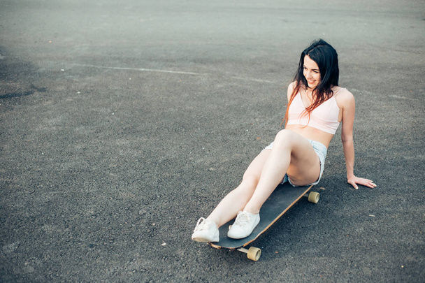 Woman with longboard sitting on the ground - Фото, изображение
