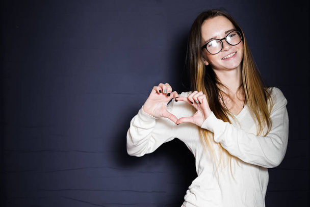 Young smiling girl with glasses shows a heart - Foto, Bild