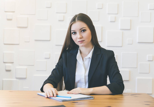 Young business woman sitting at a table, lost in thought - Photo, image