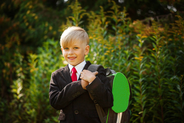 Cute boy going back to school. Boy in the suit. Closeup portrait of smiling pupil with backpack - Photo, image