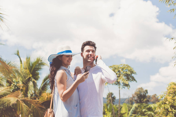 Young Couple Embracing Outdoors Using Cell Smartphones Man Talking Phone Call While Woman Chatting Online - Foto, immagini