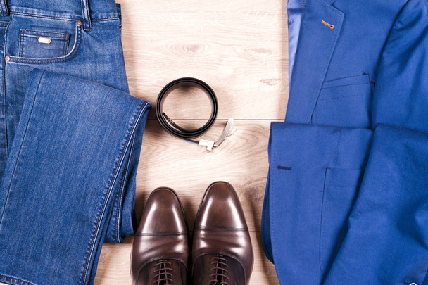 joukko klassisia miesten vaatteita sininen puku, paidat, ruskeat kengät, vyö ja solmio puinen tausta. - Valokuva, kuva