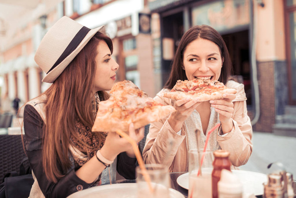 жінки їдять піцу в кафе
   - Фото, зображення