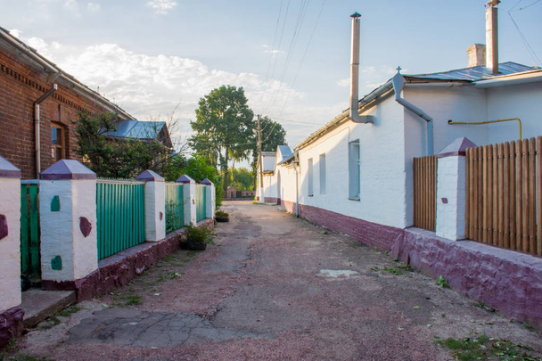 緑のフェンスと白い柱、小さな歴史的な古い町の Ovruch、ジトームィル地域、ウクライナ、昔 Drevlians のかつての首都で壁と狭い石畳。日の出の写真 - 写真・画像