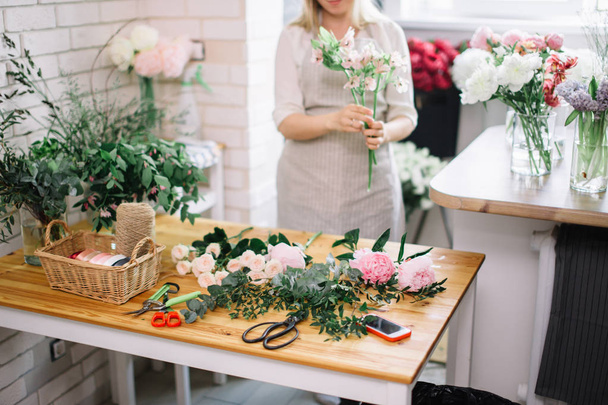Hymyilevä kaunis nuori nainen kukkakauppa järjestää kasveja kukkakauppa - Valokuva, kuva