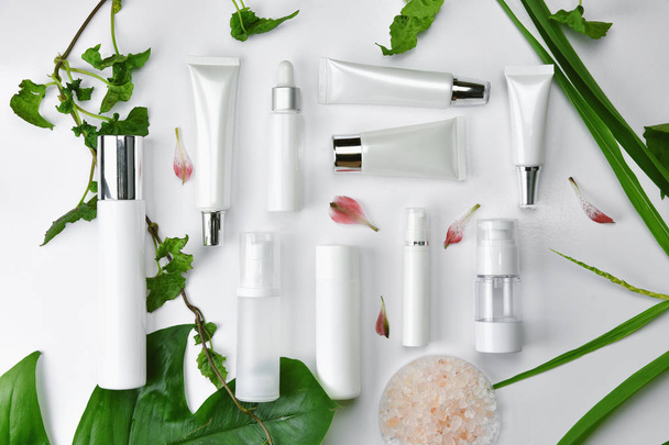 Kozmetik şişe kapları ile yeşil bitki yaprakları, marka mock-up, doğal organik güzellik ürün kavramı için boş etiket paketi. - Fotoğraf, Görsel