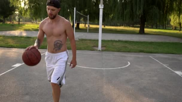 Young man plays basketball and throws the ball into the basket - Séquence, vidéo