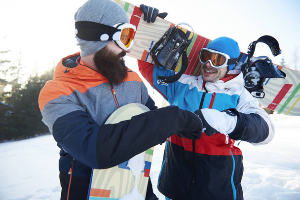 Fist bump of two male snowboarders  - Photo, Image