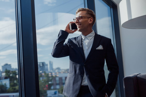 Stylish businessman talking phone in office - Фото, зображення